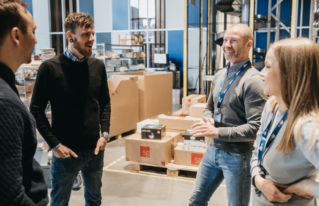 Two Element Logic employees talk to two smiling customers inside a warehouse.