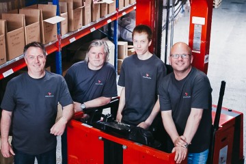 Four Colliflow employees stand in the warehouse and smile at the camera.